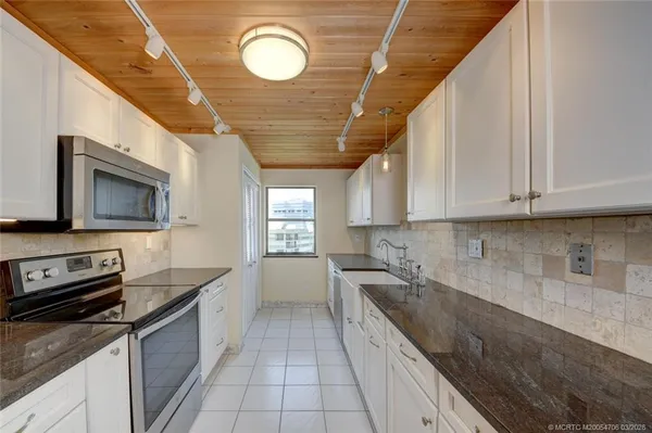 a kitchen with stainless steel appliances granite countertop a sink a stove oven and white cabinets