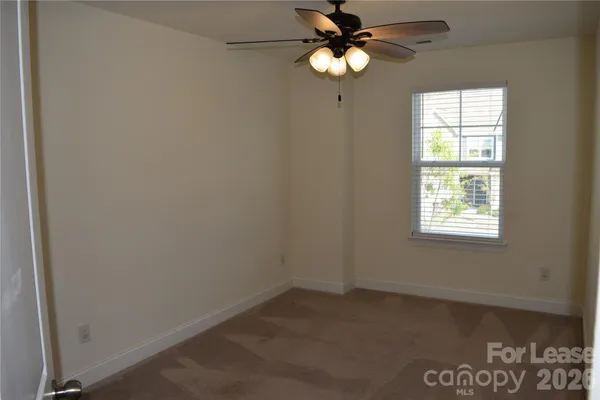 an empty room with a window and a fan