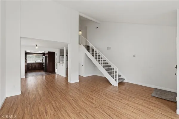 a view of an empty room with wooden floor and a fireplace