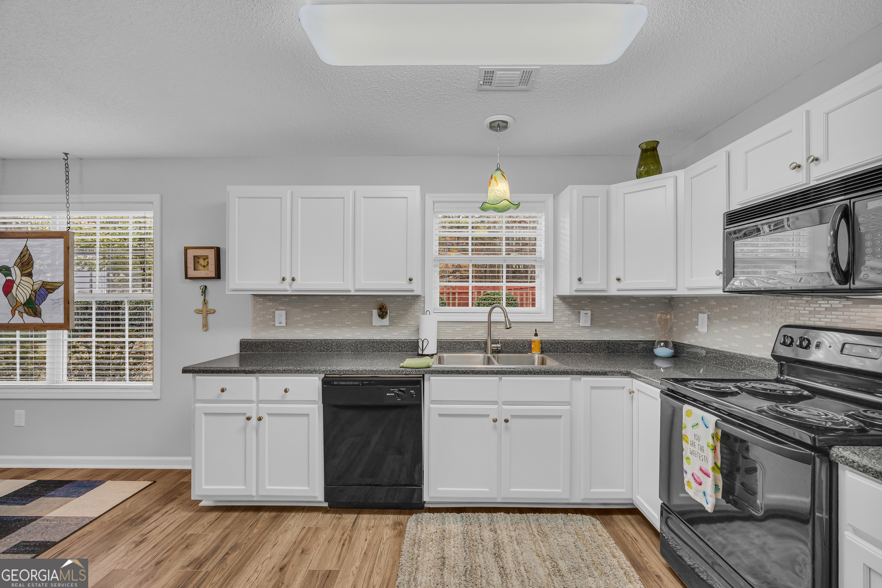 259 Watson Drive Hull, GA 30646 - Photo 28 of 47 a kitchen with stainless steel appliances granite countertop a stove a sink dishwasher and white cabinets with wooden floor