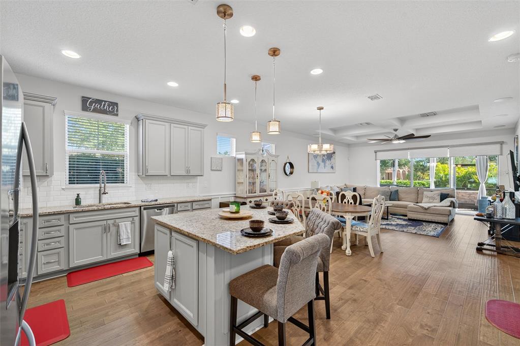 5706 Esker Falls Lane Lithia, FL 33547 - Photo 23 of 76 a kitchen with a stove a sink a kitchen island with chairs and wooden floor