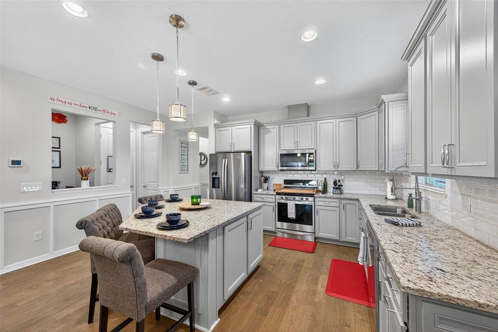 5706 Esker Falls Lane Lithia, FL 33547 - Photo 25 of 76 a kitchen with stainless steel appliances granite countertop a stove top oven a refrigerator a sink a dining table and chairs with wooden floor