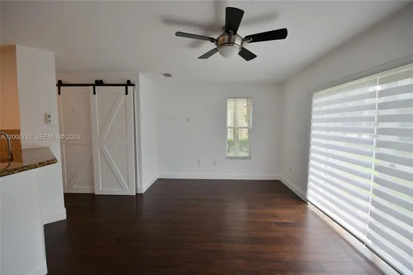 an empty room with wooden floor fan and windows