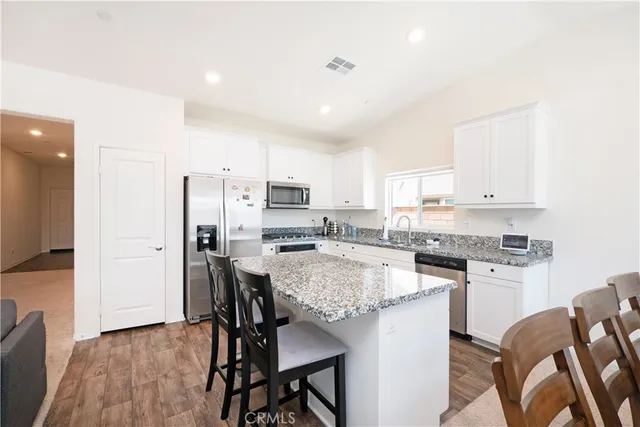 a kitchen with stainless steel appliances kitchen island granite countertop a table chairs stove and refrigerator