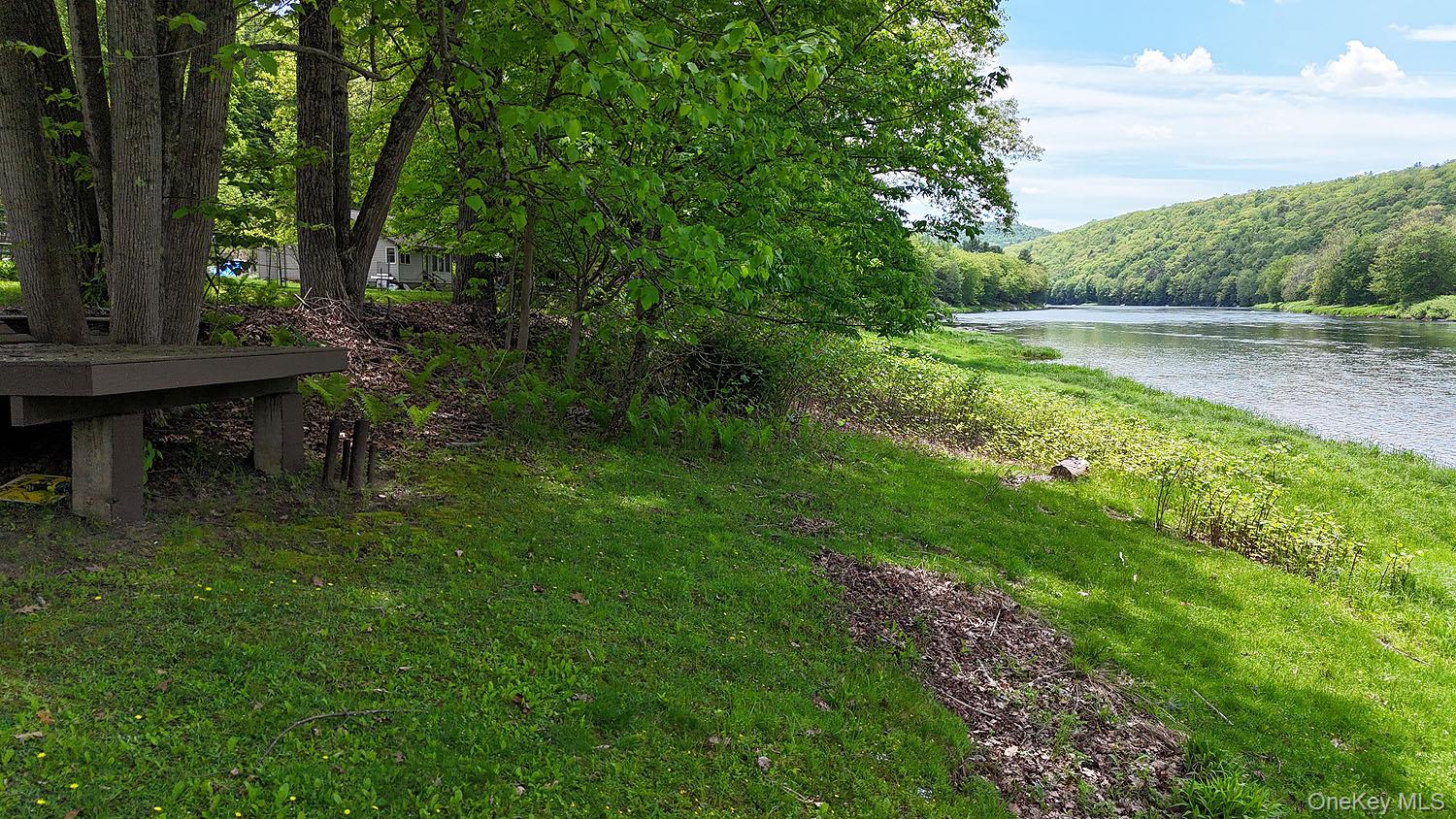 860 River Road Callicoon, NY 12723 - Photo 18 of 45 a view of a lake with a bench and a yard