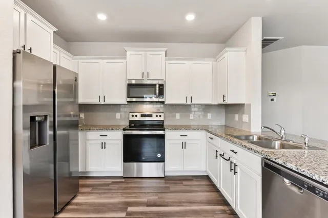 a kitchen with stainless steel appliances granite countertop a refrigerator sink and white cabinets