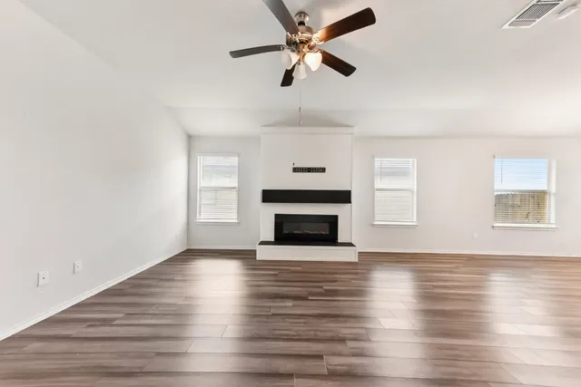 a view of a livingroom with a fireplace a ceiling fan and wooden floor