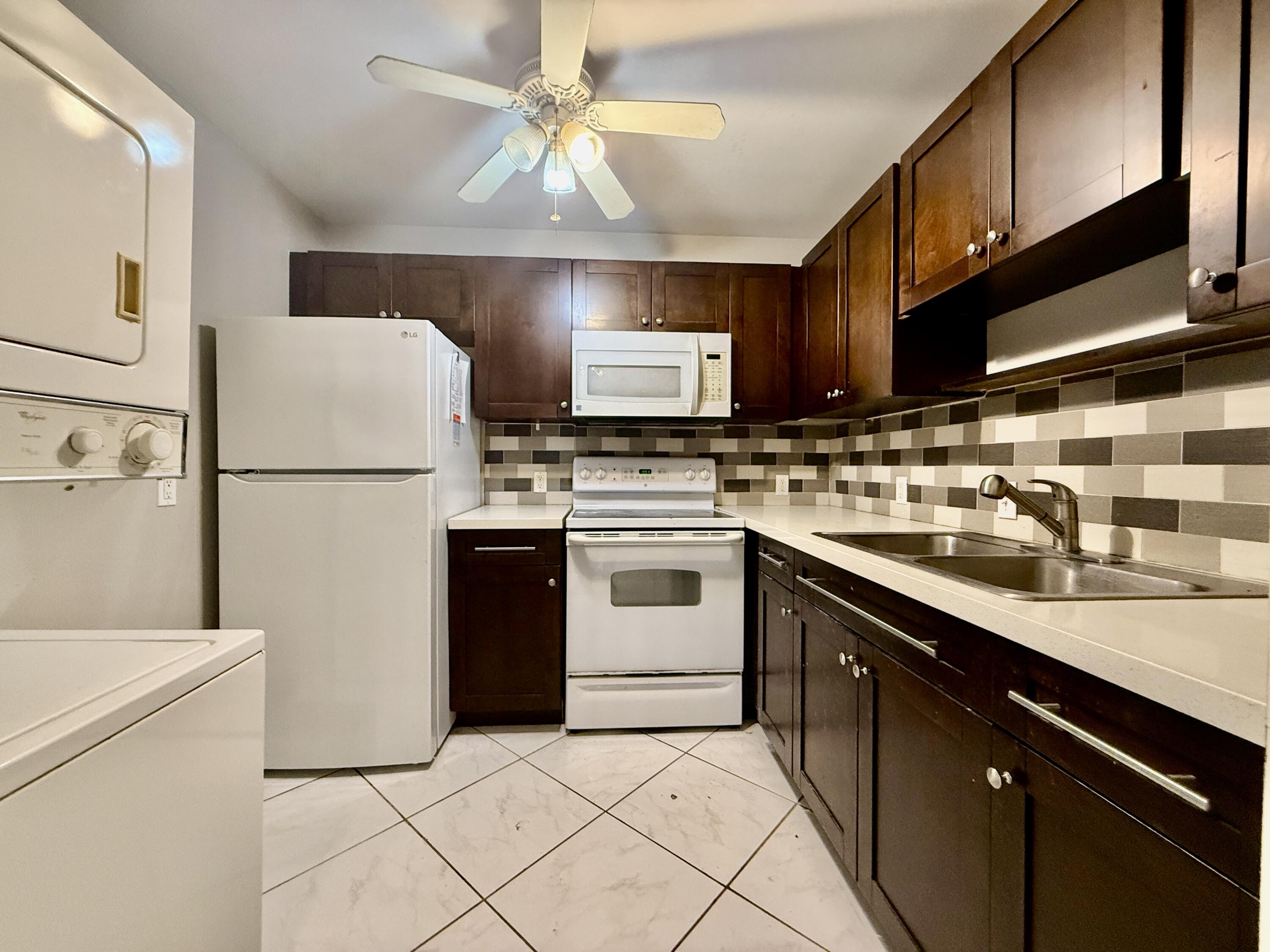 139 Tuscany Lane, Unit 139 Delray Beach, FL 33446 - Photo 4 of 21 a kitchen with a stove a sink and a refrigerator