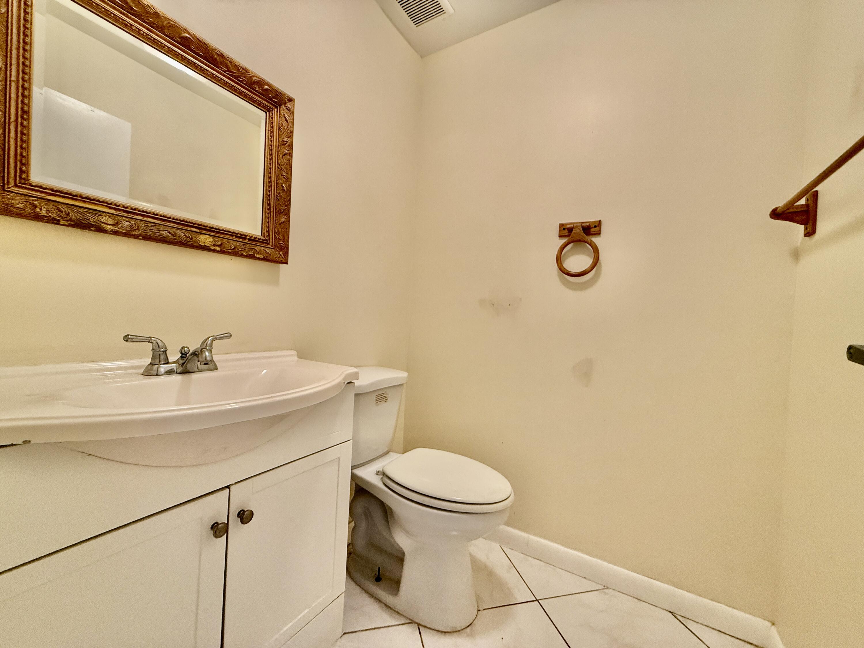 139 Tuscany Lane, Unit 139 Delray Beach, FL 33446 - Photo 6 of 21 a bathroom with a sink a toilet and mirror