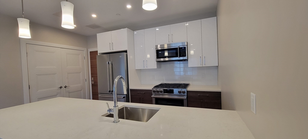 425 Lagrange Street, Unit 206 Boston, MA 02132 - Photo 6 of 15 a kitchen with stainless steel appliances a refrigerator sink and microwave
