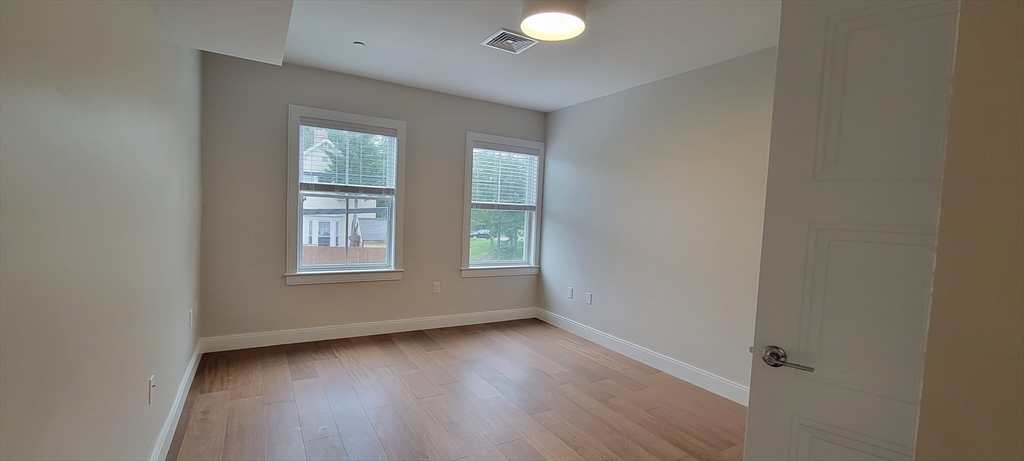 425 Lagrange Street, Unit 206 Boston, MA 02132 - Photo 10 of 15 an empty room with wooden floor and windows
