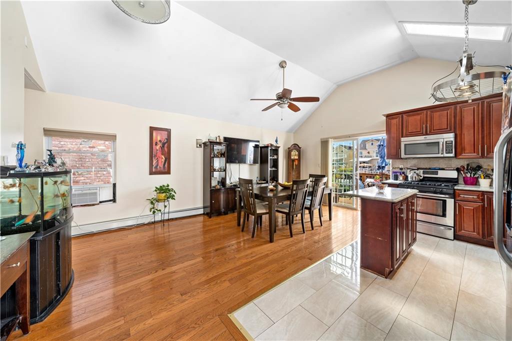 a open kitchen with stainless steel appliances granite countertop a stove top oven a sink a dining table and chairs with wooden floor