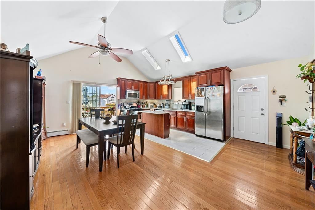 73 Bartlett Place Brooklyn, NY 11229 - Photo 2 of 14 a kitchen with stainless steel appliances kitchen island granite countertop a refrigerator a stove a dining table and chairs with wooden floor