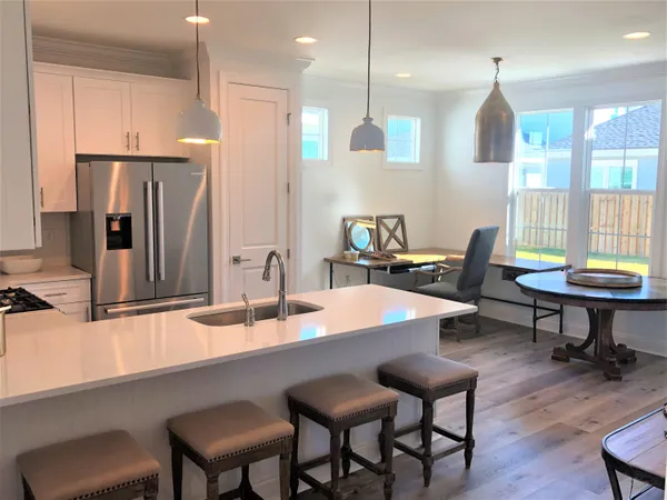 a kitchen with granite countertop a table chairs stove a refrigerator and cabinets