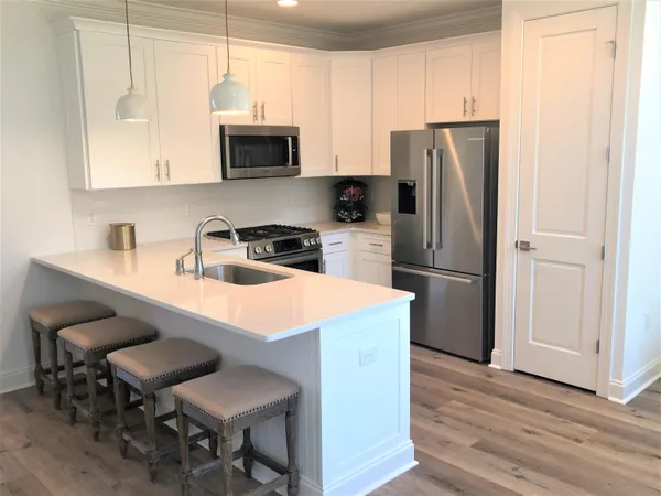 a kitchen with stainless steel appliances a stove a sink a refrigerator and microwave with wooden floor