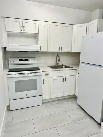a kitchen with granite countertop white cabinets and white appliances