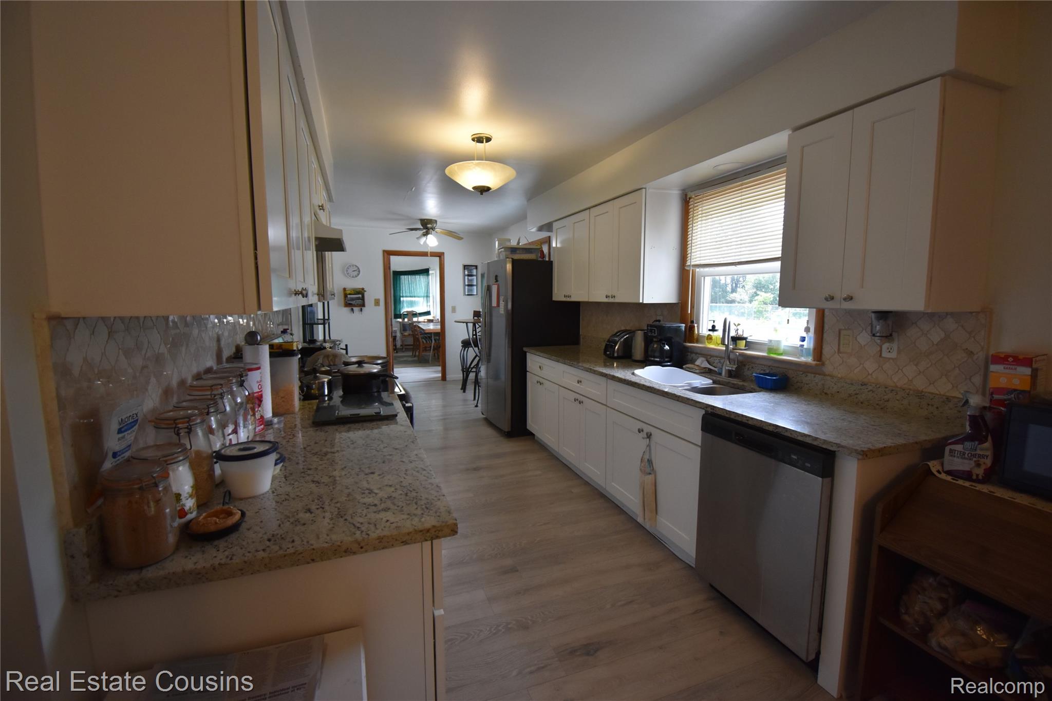 2247 Johnson Mill Road North Branch, MI 48461 - Photo 4 of 22 Kitchen featuring white cabinetry, light-toned wood-finish flooring, patterned tile backsplash, granite-style countertops, and a stainless steel dishwasher