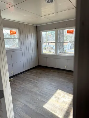 a view of an empty room with wooden floor and a window