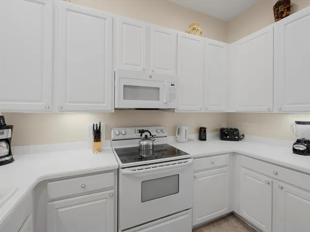 a kitchen with white cabinets and white appliances