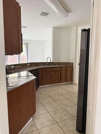 a large kitchen with a sink and a refrigerator