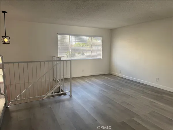 a view of an empty room with wooden floor and stairs