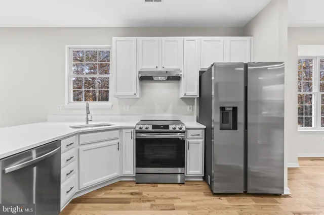 a kitchen with stainless steel appliances granite countertop a stove a refrigerator and a sink