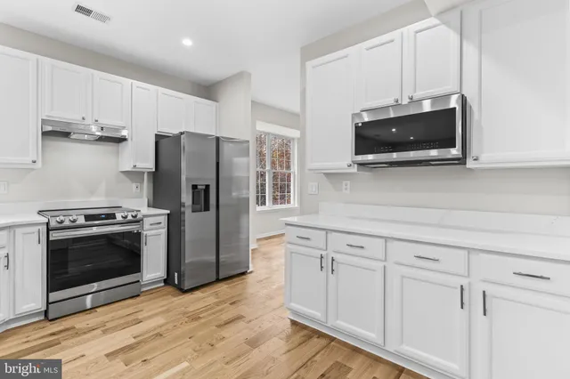 a kitchen with cabinets stainless steel appliances and wooden floor