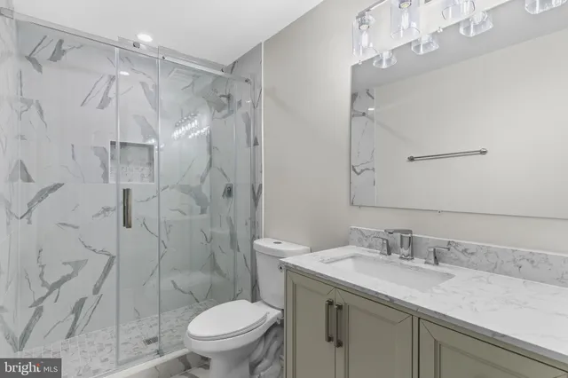 a bathroom with a granite countertop sink toilet and shower