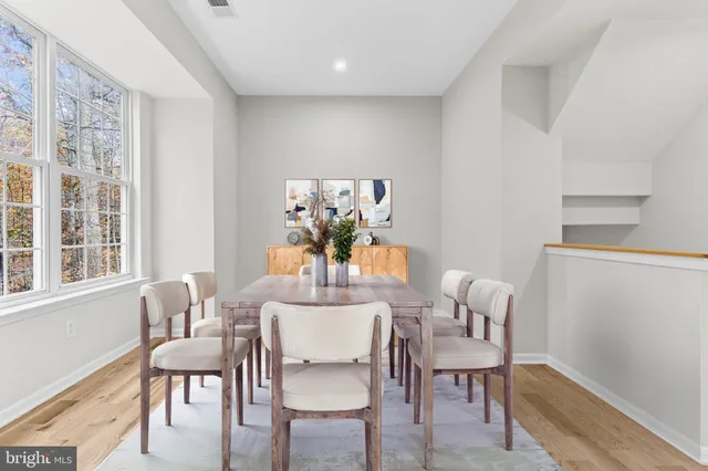 a dining room with furniture a potted plant and wooden floor
