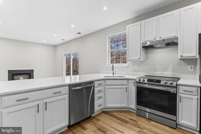 a kitchen with cabinets stainless steel appliances and wooden floor