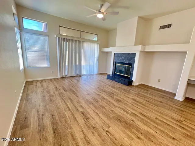 a view of an empty room with wooden floor fireplace and a window