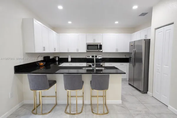 a kitchen with stainless steel appliances granite countertop a sink a stove a refrigerator cabinets and chairs