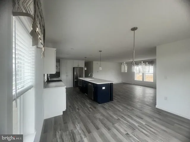 a kitchen with stainless steel appliances granite countertop a refrigerator a sink dishwasher a stove and a wooden floors