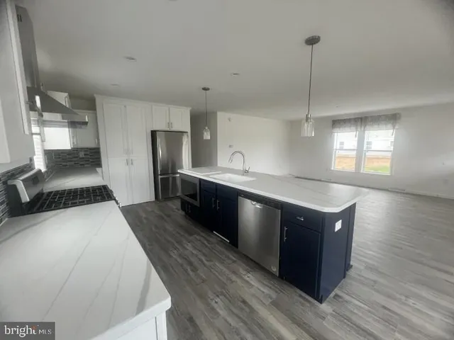 a kitchen with stainless steel appliances granite countertop a sink a stove and a wooden floor