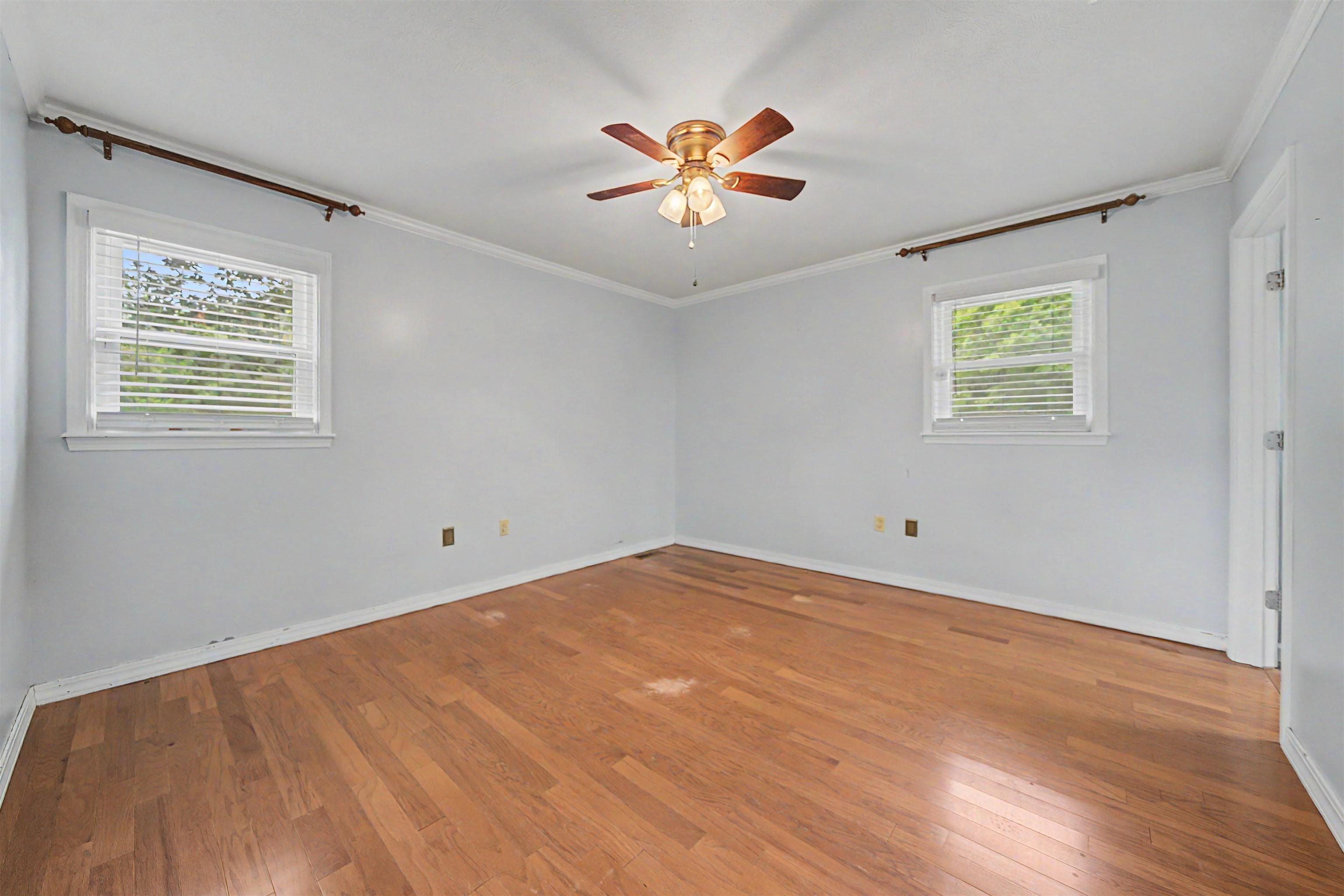 436 Skyline Road Selmer, TN 38375 - Photo 24 of 40 Room with wood-finish flooring, two windows with blinds, a ceiling fan with light fixture, white crown molding, and baseboards
