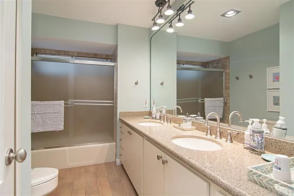 a bathroom with a granite countertop bathtub shower sink vanity and toilet