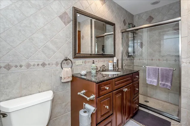 a bathroom with a granite countertop sink a toilet and a shower