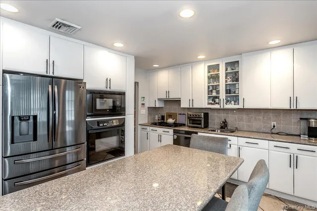 a kitchen with granite countertop a refrigerator stove microwave and sink