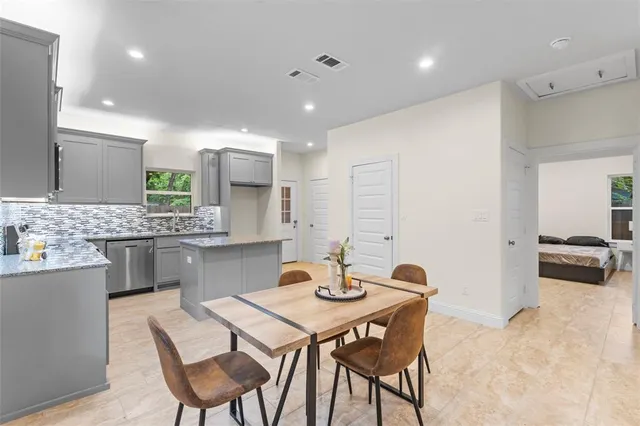 a kitchen with a table chairs sink and white cabinets
