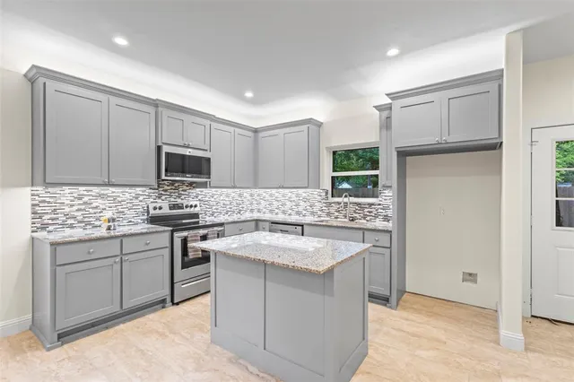 a kitchen with stainless steel appliances kitchen island granite countertop a sink stove and granite counter top