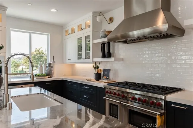 a kitchen with a stove a sink a window and cabinets