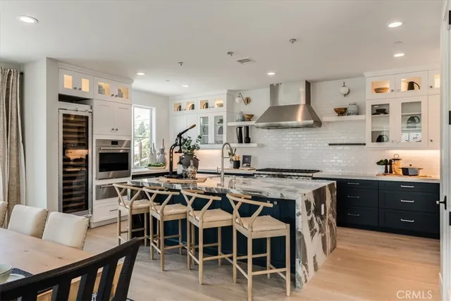 a kitchen with stainless steel appliances granite countertop a stove top oven a sink a dining table and chairs