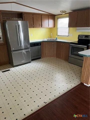 a kitchen with granite countertop a stove a sink and a refrigerator