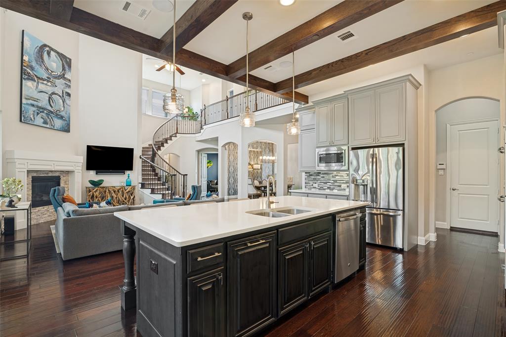 388 Bethany Road Sunnyvale, TX 75182 - Photo 13 of 40 Open-concept kitchen featuring an island with a dual-basin undermount sink, light-toned countertops, and dark wood-finish cabinetry