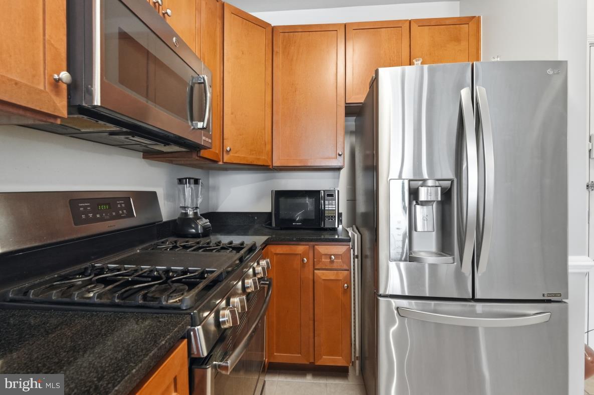 8045 Newell Street, Unit 423 Silver Spring, MD 20910 - Photo 17 of 26 a kitchen with stainless steel appliances granite countertop a refrigerator stove and microwave