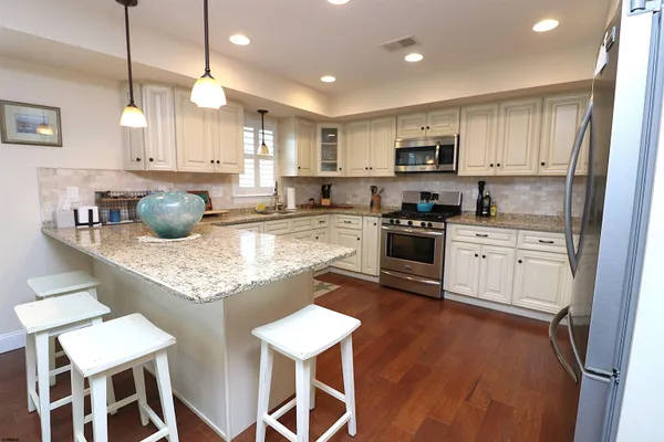 a white kitchen with granite countertop white cabinets and white appliances