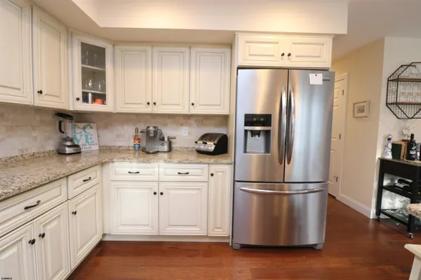 a kitchen with stainless steel appliances granite countertop a refrigerator a sink a stove and a wooden floors