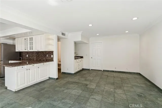 a large kitchen with granite countertop a sink white cabinets and stainless steel appliances