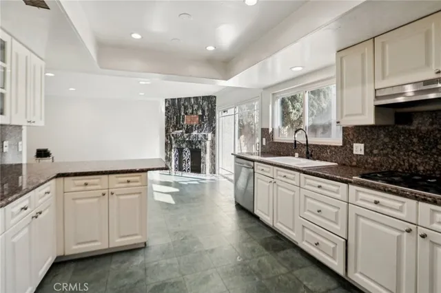 a kitchen with granite countertop a sink a stove a refrigerator and white cabinets
