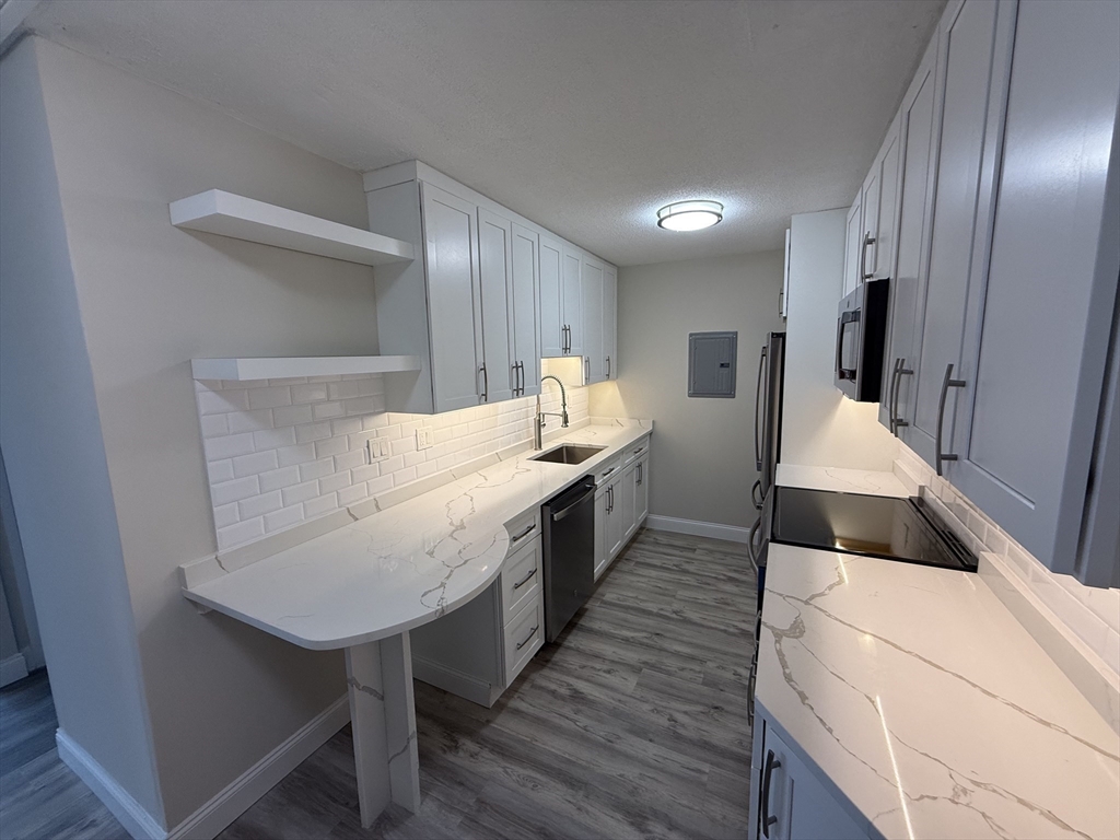 566 Commonwealth Avenue, Unit 308 Boston, MA 02215 - Photo 4 of 14 a kitchen with a sink and wooden cabinets